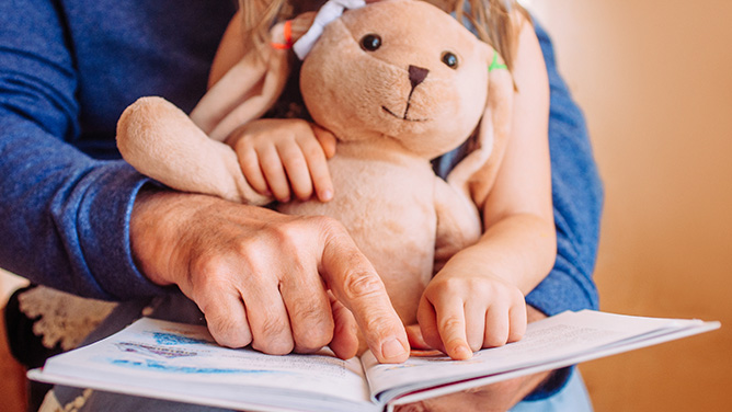 child reading with a teddy bear