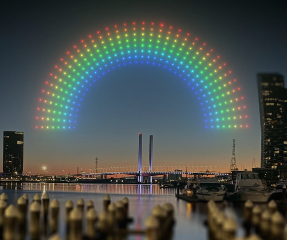 A neon rainbow projected in the sky above Docklands
