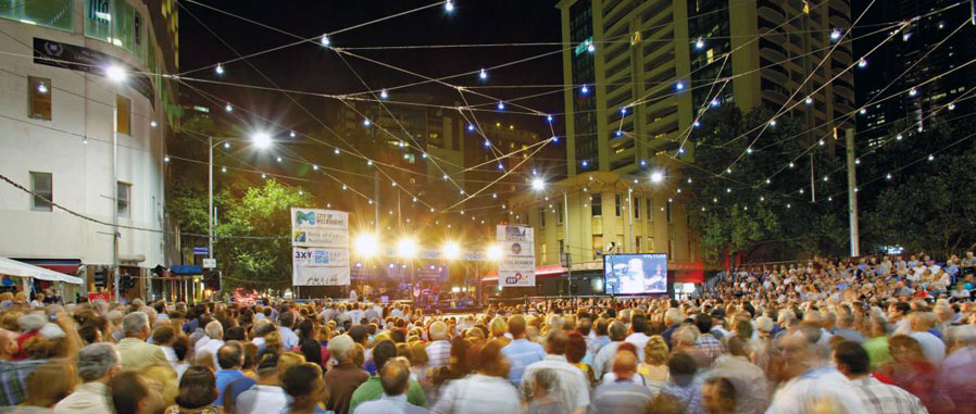 Large crowd of people under festive lights at a street festival